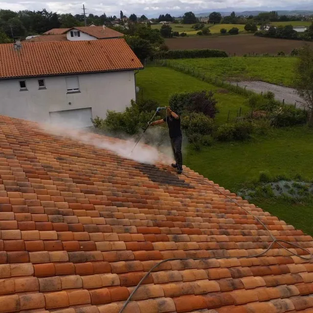 Traitement vapeur anti-mousse en cours sur une toiture en tuiles dans les Landes